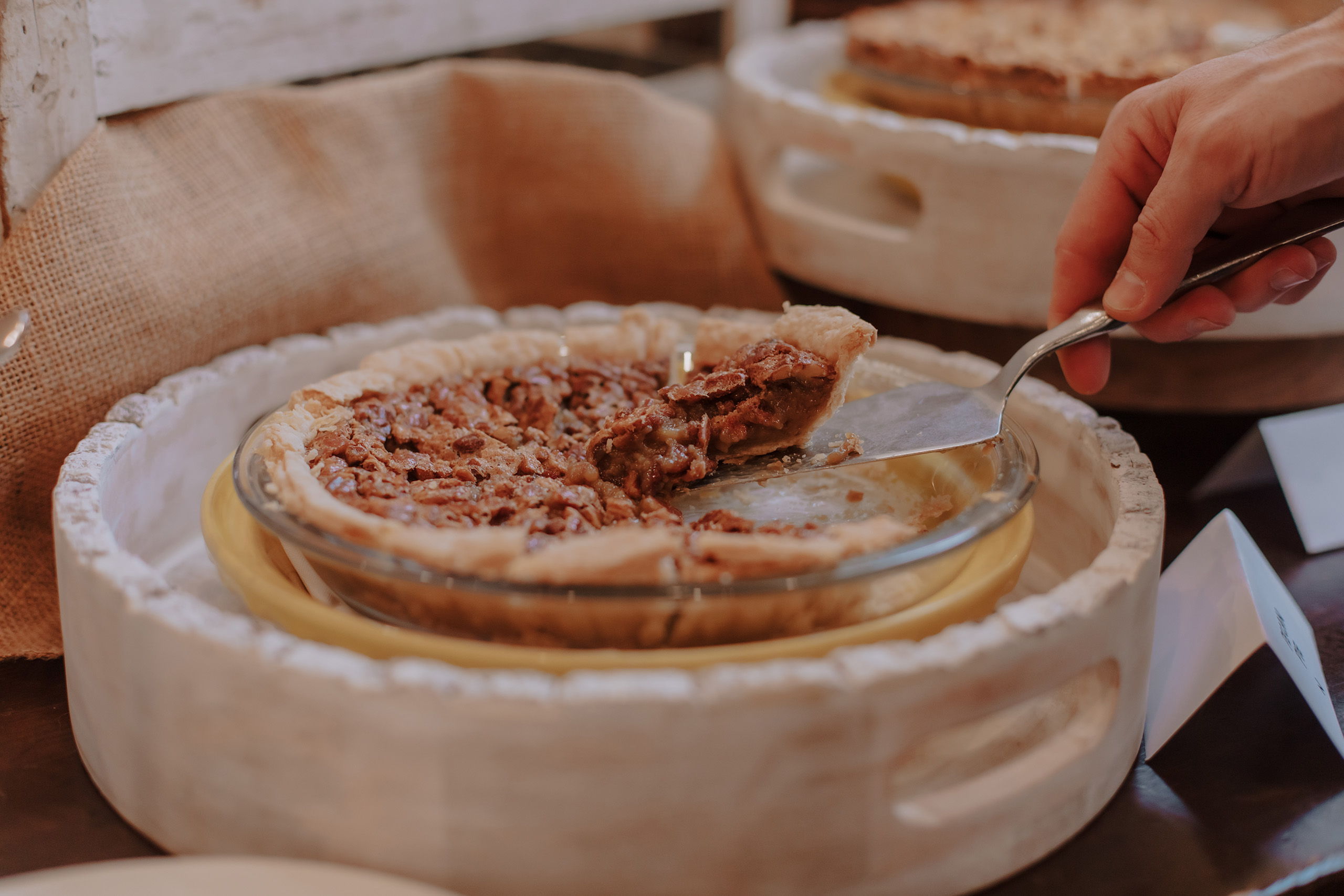 Undistinguishable person taking a slice of pecan pie